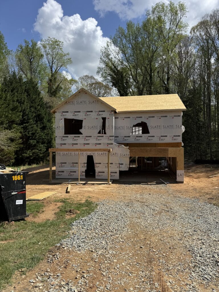 Framing of a two-story home under construction on a wooded lot