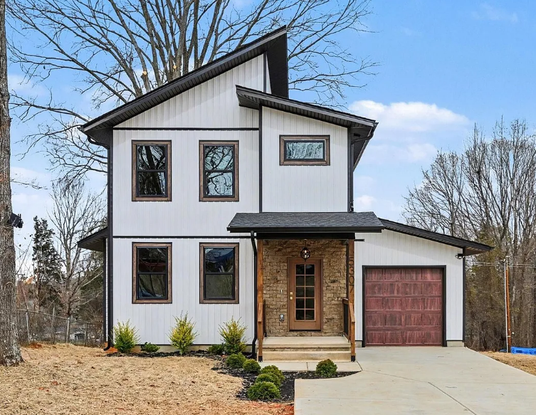 Two-story home with white siding, black windows, and a brick-accented entry